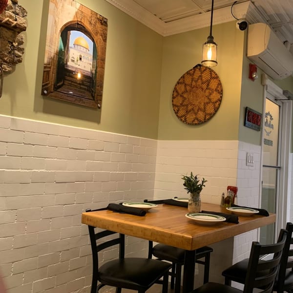 A cozy corner of The Olive Bistro with a wooden table set for two, Palestinian decor on the walls.