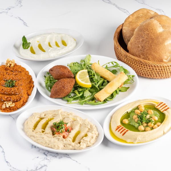 A spread of Middle Eastern appetizers including hummus, baba ghanoush, kibbeh, and pita bread.