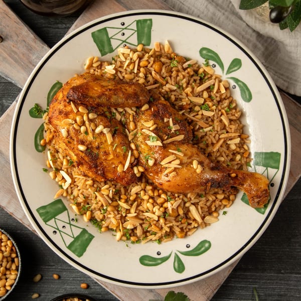 Palestinian Musakhan chicken with rice, pine nuts, and almonds on a decorative plate.