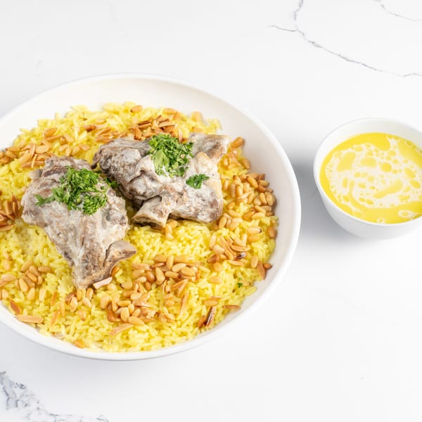 Mansaf with tender lamb, yellow rice, pine nuts, and a side of jameed sauce.