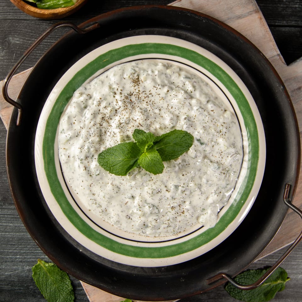 Palestinian yogurt dip, labneh, garnished with mint and spices in a green-striped bowl.