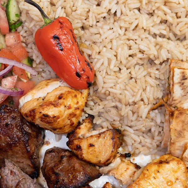 Palestinian dish with grilled chicken and beef, rice, salad, and a roasted red pepper.