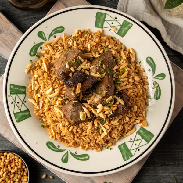 Palestinian Mansaf with rice, lamb, pine nuts, and almonds on a decorative plate.