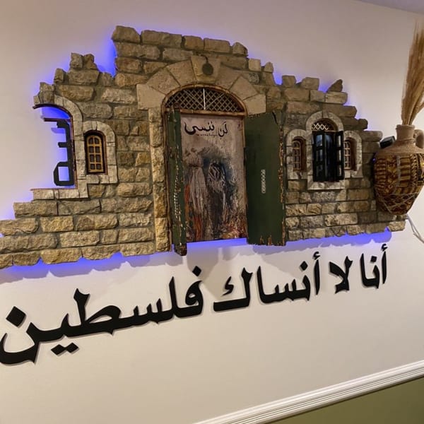 A stone wall decoration with blue backlighting, a door, windows, and Arabic calligraphy below.