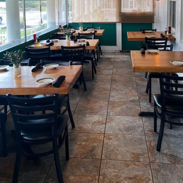 The Olive Bistro dining room with wooden tables, black chairs, and large windows overlooking outside.